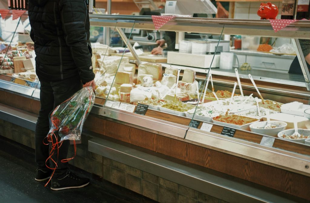 homme avec un bouquet de roses debout devant un présentoir de nourriture